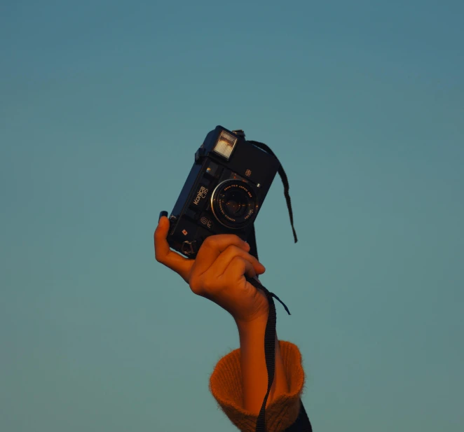 a person holding a camera up in the air, a picture, with a blue background, low contrast, clear sky, low quality photo