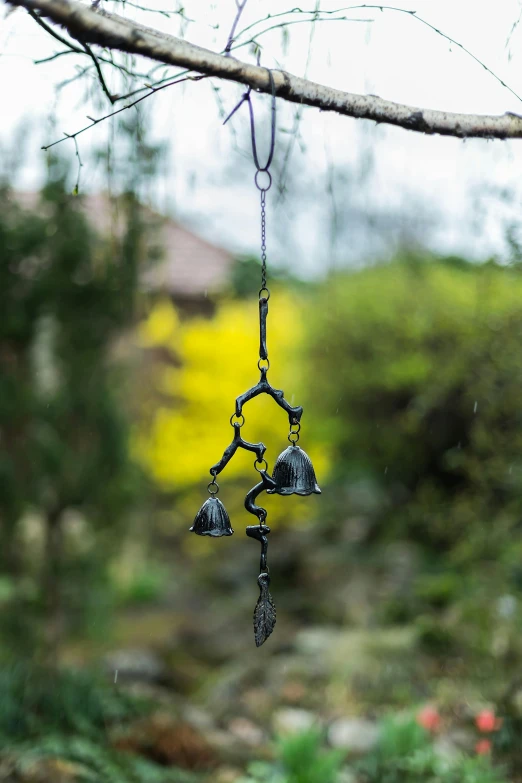 a metal bell hanging from a tree branch, inspired by Diego Giacometti, kinetic art, lisa parker, hanging lanterns, rainy day outside, angled shot
