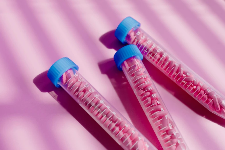 a couple of toothbrushes sitting on top of a pink surface, by Rachel Reckitt, trending on pexels, process art, pathology sample test tubes, featuring pink brains, made of candy, vibrant vials