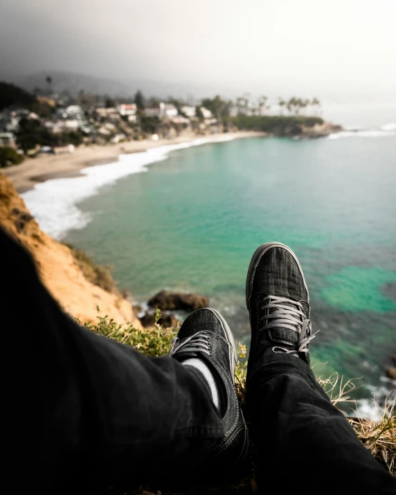 a person sitting on top of a hill next to the ocean, sneaker photo, lgbtq, 5 feet distance from the camera, pov photo