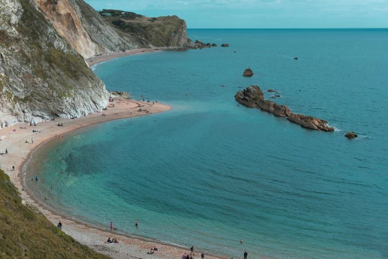 a group of people standing on top of a sandy beach, coastal cliffs, crystal clear blue water, devon cady-lee, slide show