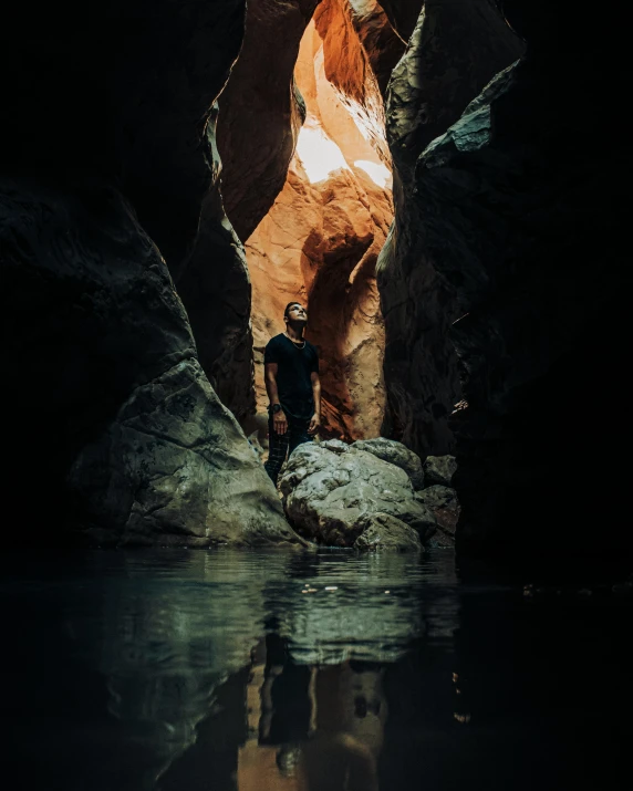 a man standing on top of a rock next to a body of water, a cave painting, by Jessie Algie, unsplash contest winner, australian tonalism, marble hole, inside mirror, arches, hollow cheeks