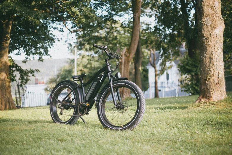 a bicycle that is sitting in the grass, in the sun