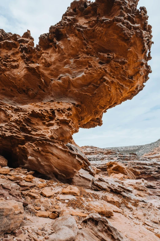 a large rock formation in the middle of a desert, by Lee Loughridge, unsplash contest winner, australian tonalism, large overhangs, bent rusted iron, gooey, red ocher