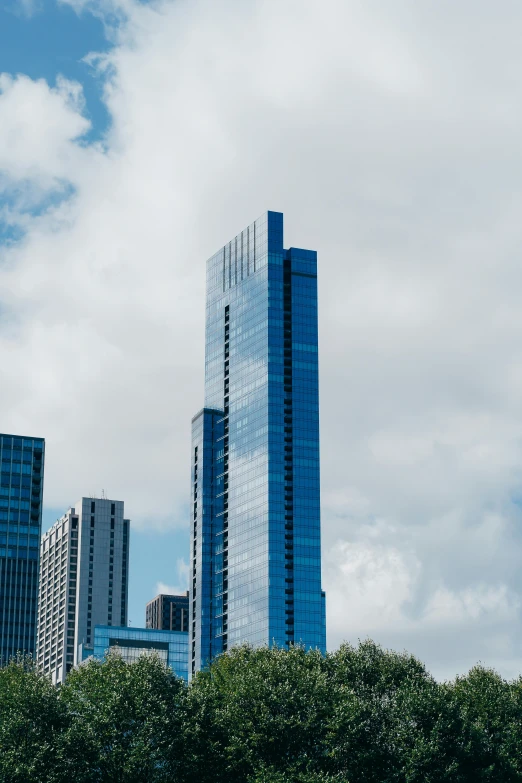 a city skyline with skyscrapers and trees in the foreground, an album cover, unsplash, modernism, under blue clouds, tall thin build, chicago, huge glass structure