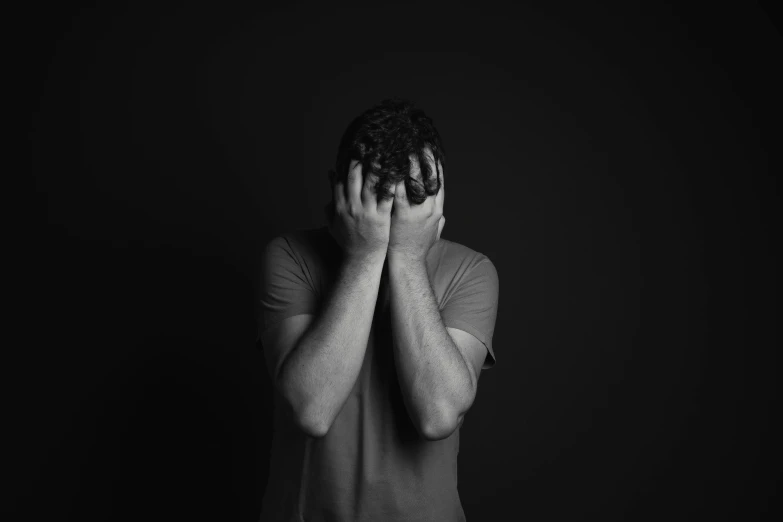 a man covering his face with his hands, a black and white photo, pexels, standing in a dark, woman crying, man standing in defensive pose, recovering from pain