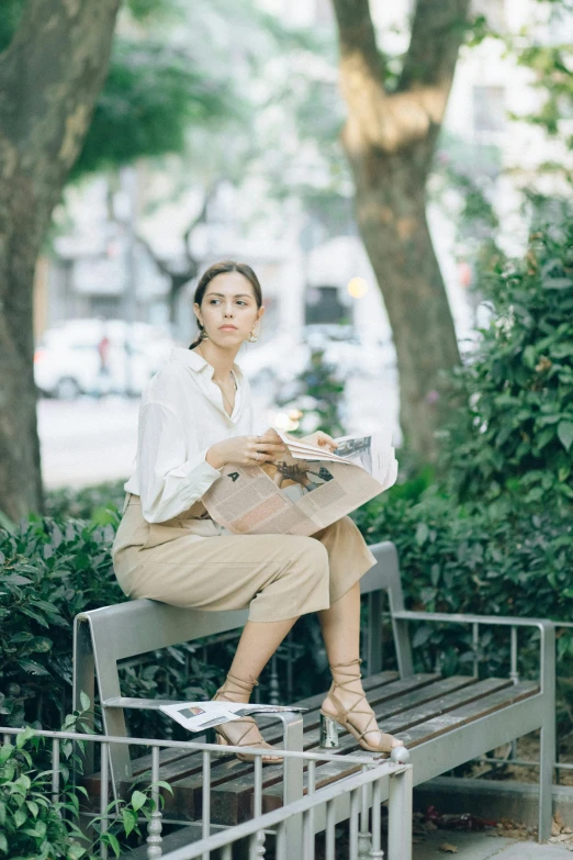 a woman sitting on a bench reading a newspaper, wearing a linen shirt, jc park, julia sarda, very professional
