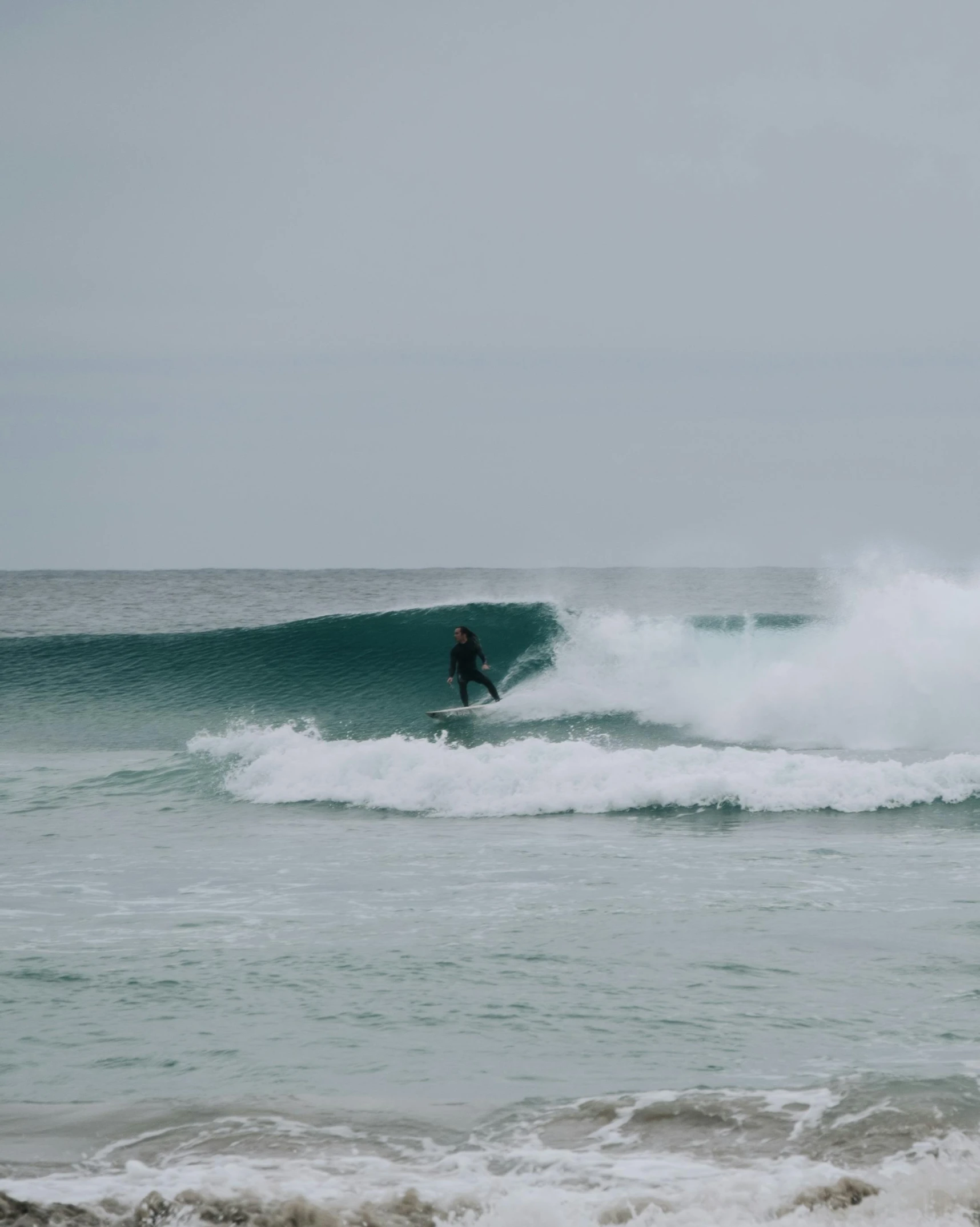 a man riding a wave on top of a surfboard, by Robbie Trevino, pexels contest winner, hurufiyya, slight overcast, lachlan bailey, the emerald coast, low quality photo