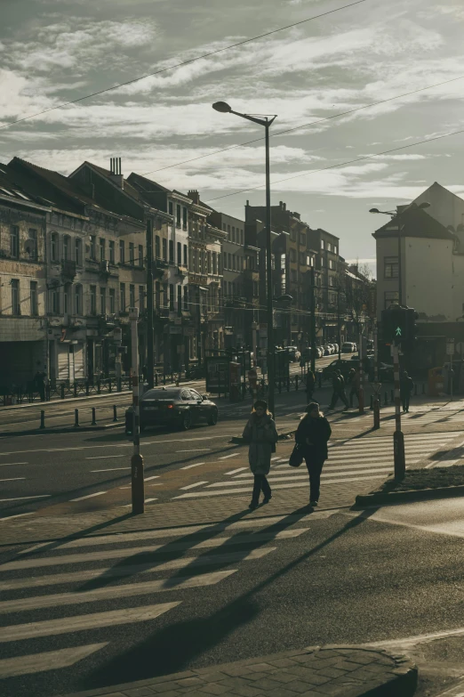 a couple of people walking across a street, by Jan Tengnagel, pexels contest winner, late afternoon light, moor, city panorama, belgium