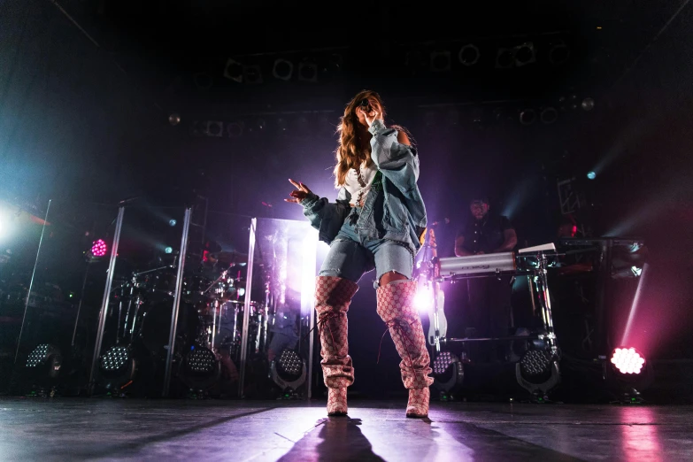 a woman that is standing on a stage, an album cover, by Robbie Trevino, pexels, holography, bella thorne, in tokio, concert, wearing a baggy