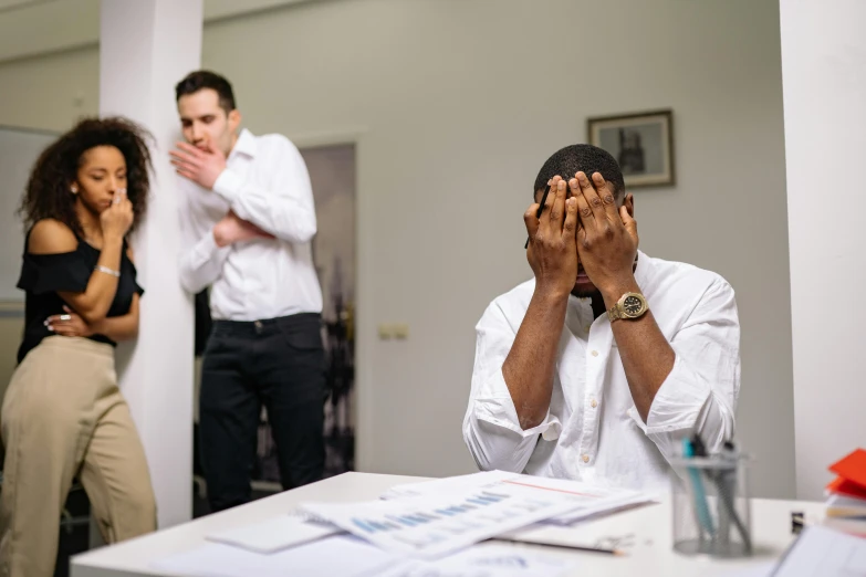 a man covering his face in front of a woman, stressed, black man, in an office, multiple stories