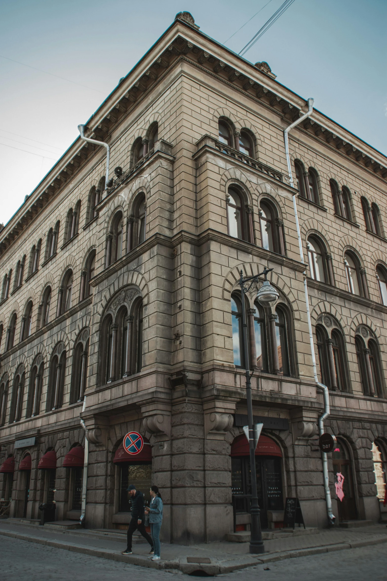 a tall building sitting on the corner of a street, inspired by Heinrich Danioth, art nouveau, helsinki, stone facade, over-shoulder shot, shot with sony alpha 1 camera