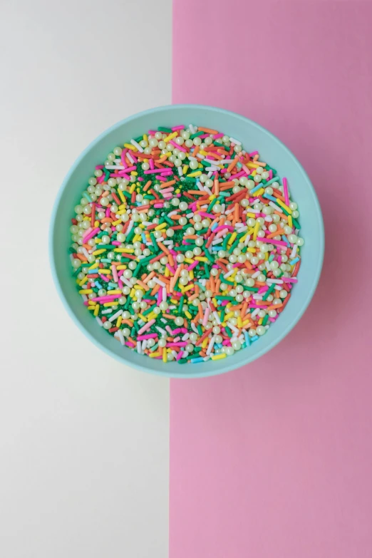 a bowl of sprinkles on a pink and white background, by Winona Nelson, trending on unsplash, turquoise pink and yellow, made of food, greens), on a dark background