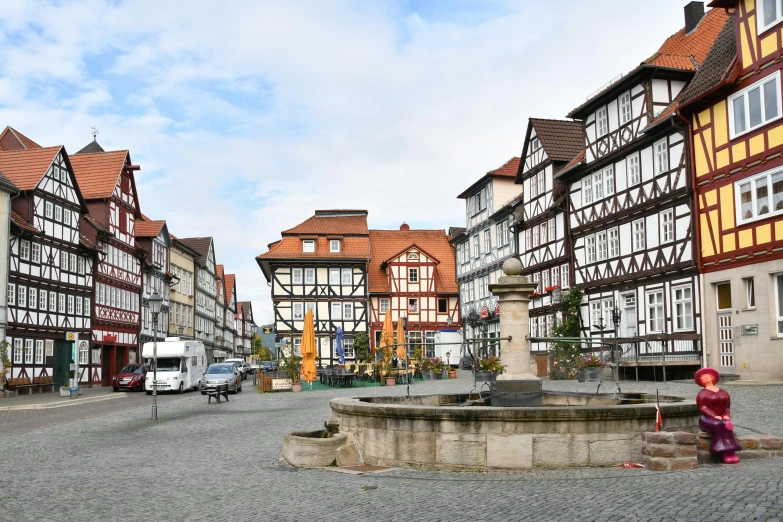 a red fire hydrant sitting in the middle of a street, by Matthias Stom, pexels contest winner, renaissance, timbered house with bricks, detmold, fountain in the middle, slide show