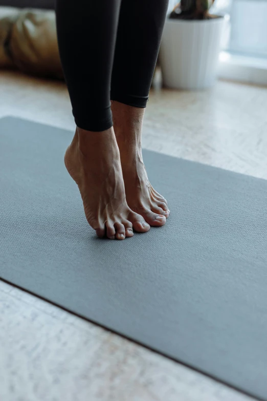 a woman standing on top of a yoga mat, unsplash, realistic human feet, grey, carefully crafted, warm