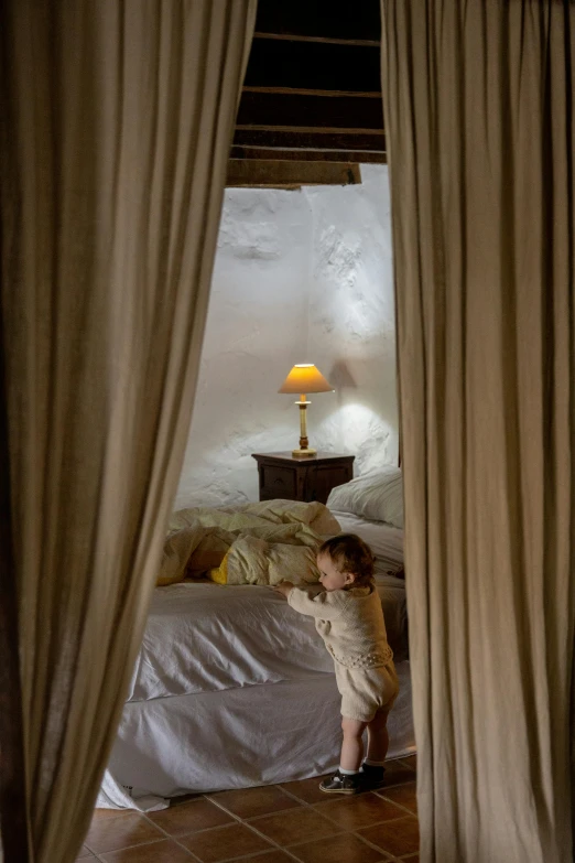 a little girl that is standing in front of a bed, inspired by Pierre Auguste Cot, unsplash contest winner, interior of a hobbit hole, soft warm lighting, lined in cotton, drapes