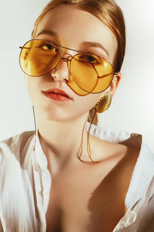 a woman wearing sunglasses and a white shirt, inspired by Bert Stern, trending on pexels, gold wings, gold cables, demna gvasalia, wearing honey