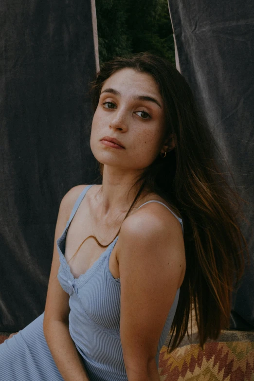 a woman in a blue dress sitting on a couch, inspired by Elsa Bleda, trending on pexels, renaissance, natalia dyer, sweaty face, bralette, solid background