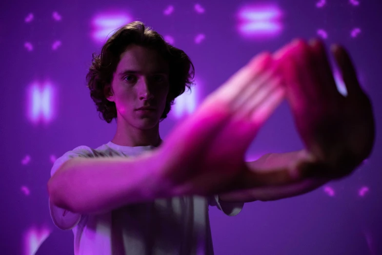 a man standing in front of a purple light, pexels contest winner, interactive art, timothee chalamet, elongated arms, soft light 4 k in pink, male teenager