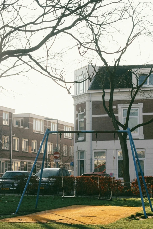 a child's swing set in a park in front of a building, by Jacob Toorenvliet, bay window, white houses, fzd school of design, very low quality