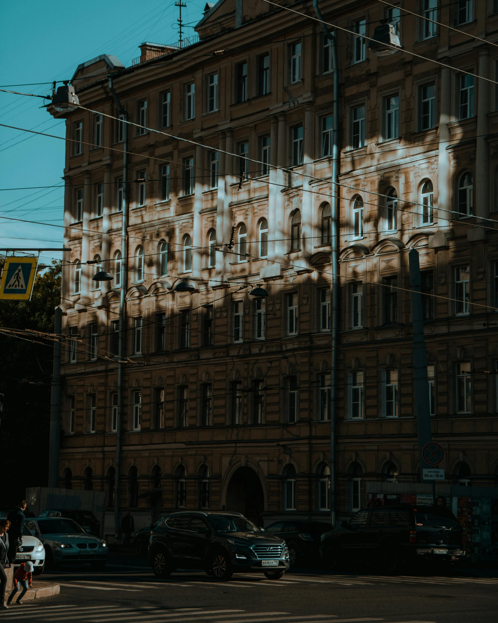 a man riding a skateboard down a street next to a tall building, by Emma Andijewska, pexels contest winner, socialist realism, sun shines down on the car, soviet apartment building, light reflecting off windows, old building