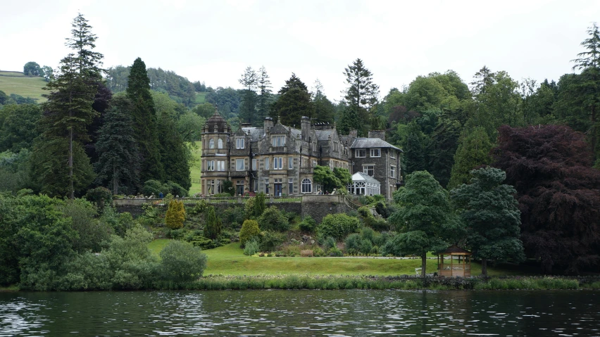 a large house sitting on top of a lush green hillside, inspired by Edwin Deakin, renaissance, on a lake, staggered terraces, grey skies, exterior photo