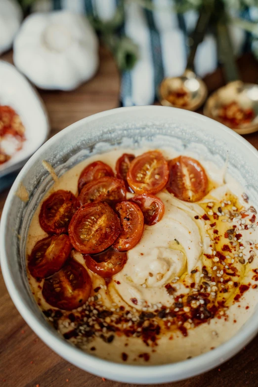 a close up of a bowl of food on a table, by Daniel Lieske, trending on unsplash, tomato splatter, humus, gold, manuka