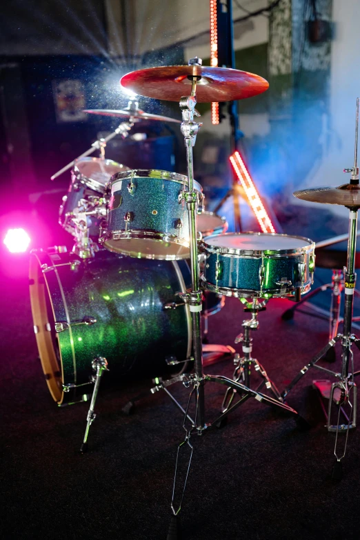 a close up of a drum set on a stage, by Dave Melvin, holography, studio lightning, green and blue color scheme, metal readymade, most popular