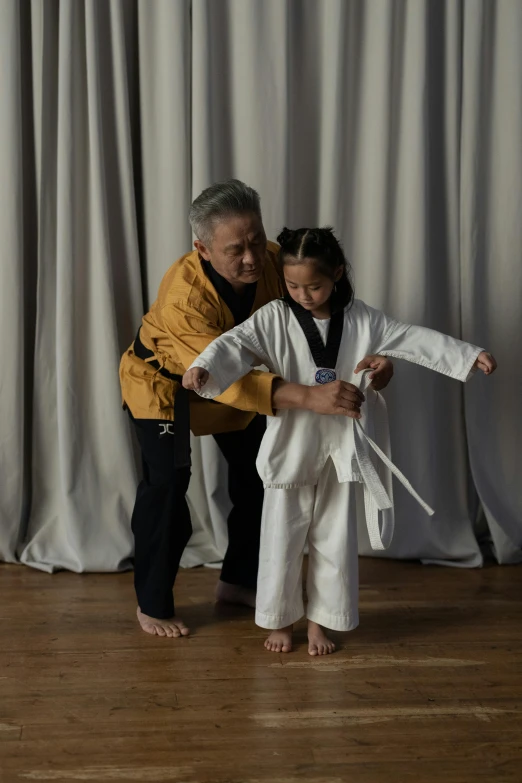 a man standing next to a little girl on a wooden floor, inspired by Kanō Shōsenin, instruction, wearing silver silk robe, grading, darren quach