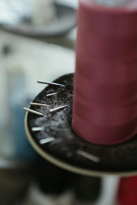 a pink candle sitting on top of a black plate, a picture, unsplash, process art, seams stitched tightly, threads, tailored clothing, cone