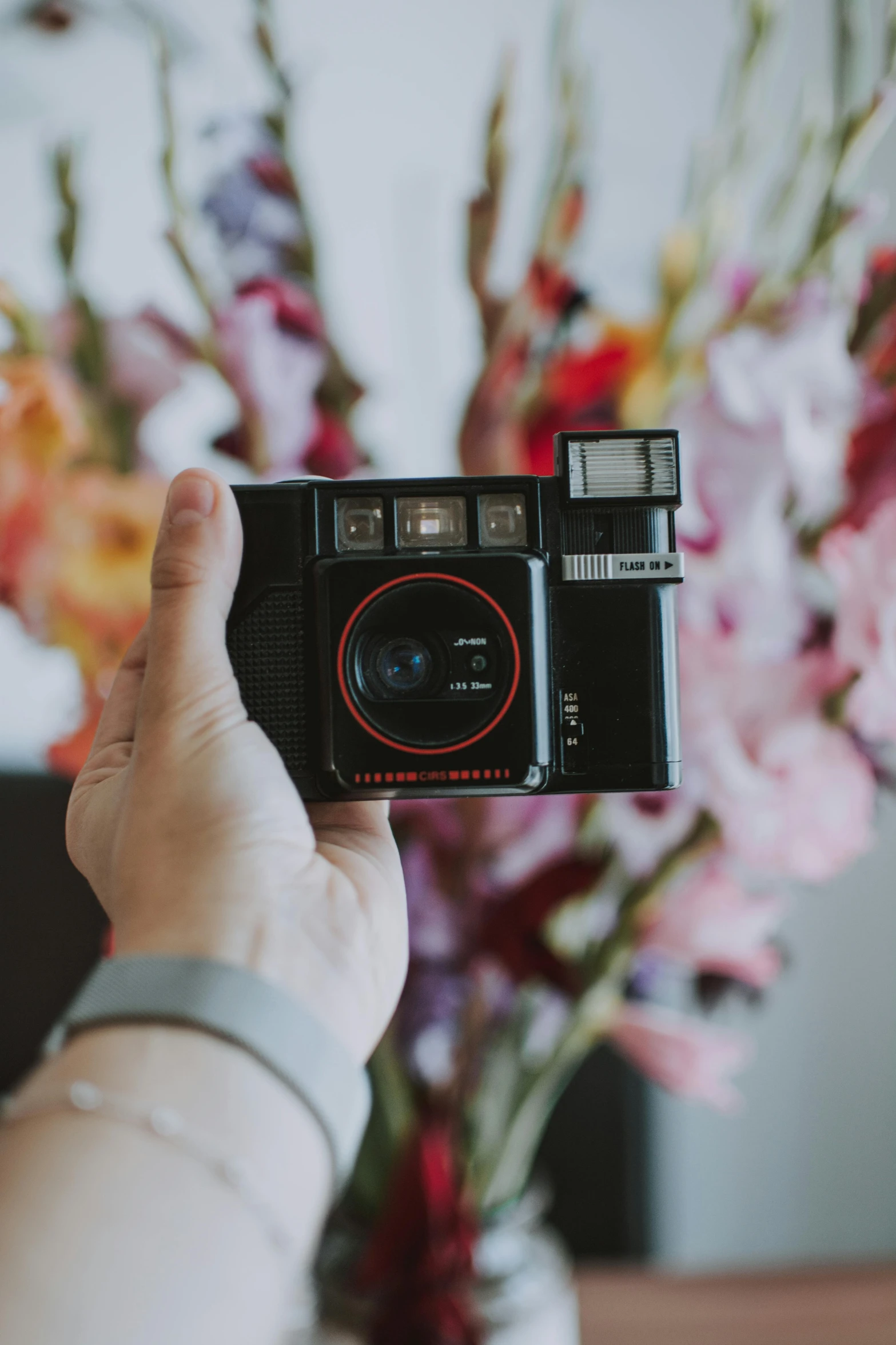 a person taking a picture with a camera, a polaroid photo, inspired by Nan Goldin, unsplash contest winner, flowers, hasselblad film bokeh, home video footage, red camera