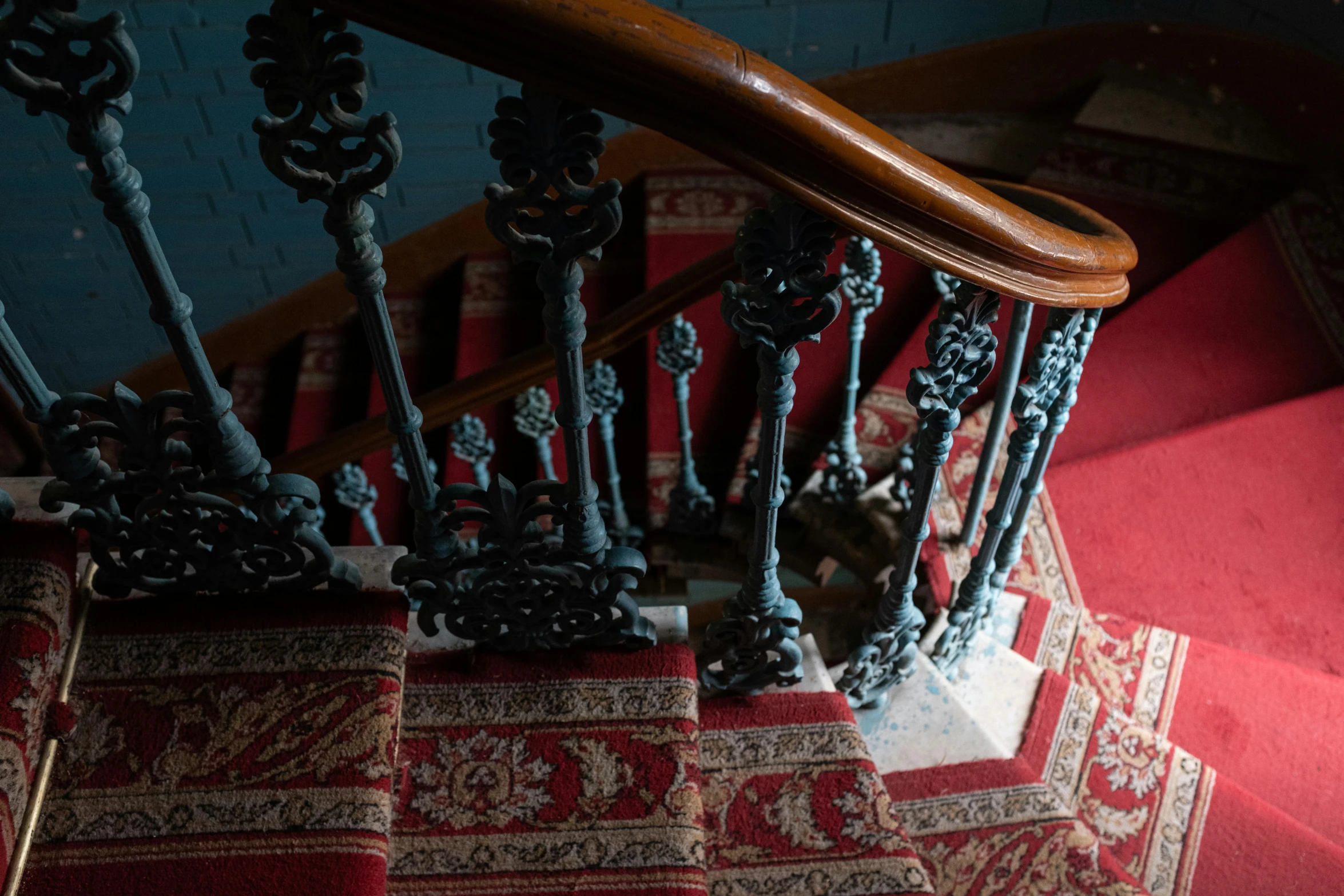 a cat sitting at the bottom of a set of stairs, by Elsa Bleda, unsplash contest winner, arts and crafts movement, red brocade and blue gemstones, interior of a victorian house, iron railing, carpet