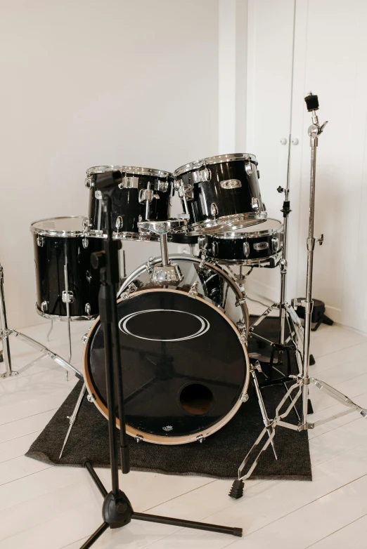 a drum kit sitting on top of a hard wood floor, in front of white back drop, it has six thrusters in the back, photo of a model, high-quality photo