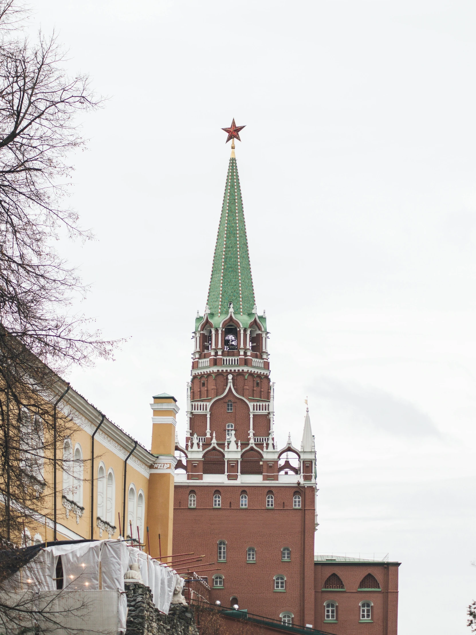 a group of people walking down a street next to tall buildings, an album cover, inspired by Vasily Surikov, trending on unsplash, socialist realism, moscow kremlin, cold as ice! 🧊, red white and gold color scheme, monument