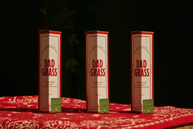 a couple of boxes sitting on top of a table, red grass, dad energy, full product shot, oud