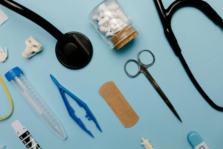 a variety of medical supplies laid out on a blue surface, a picture, by Kristian Zahrtmann, trending on pexels, plasticien, scissors, brown, blue and black scheme, small details