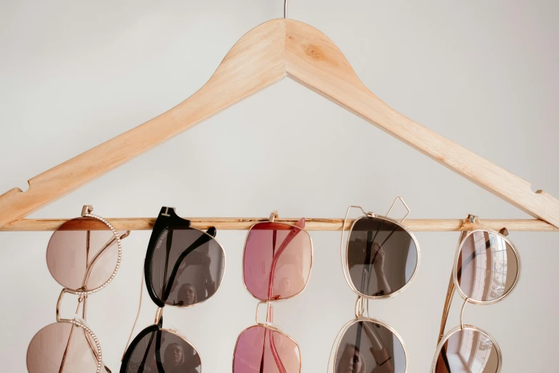 several pairs of sunglasses hanging from a wooden hanger, by Matija Jama, trending on pexels, laundry hanging, small square glasses, bralette, half image
