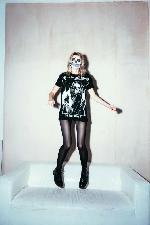 a woman standing on top of a white couch, lowbrow, punk rock clothes, skeleton face, kate moss, official store photo