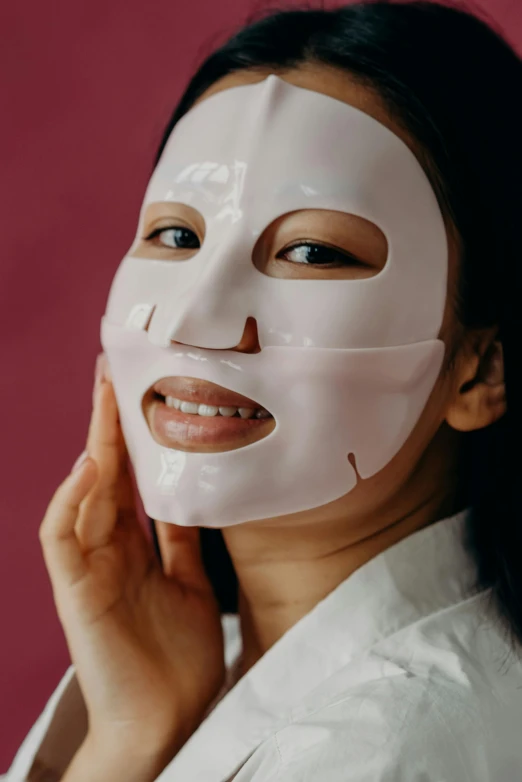 a woman with a sheet mask on her face, trending on pexels, portrait of modern darna, glowing pink face, front on, silicone skin