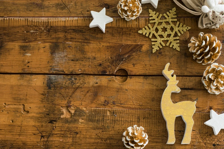 a wooden table topped with pine cones and decorations, a cartoon, trending on pexels, stars, brown and gold, deer, wooden