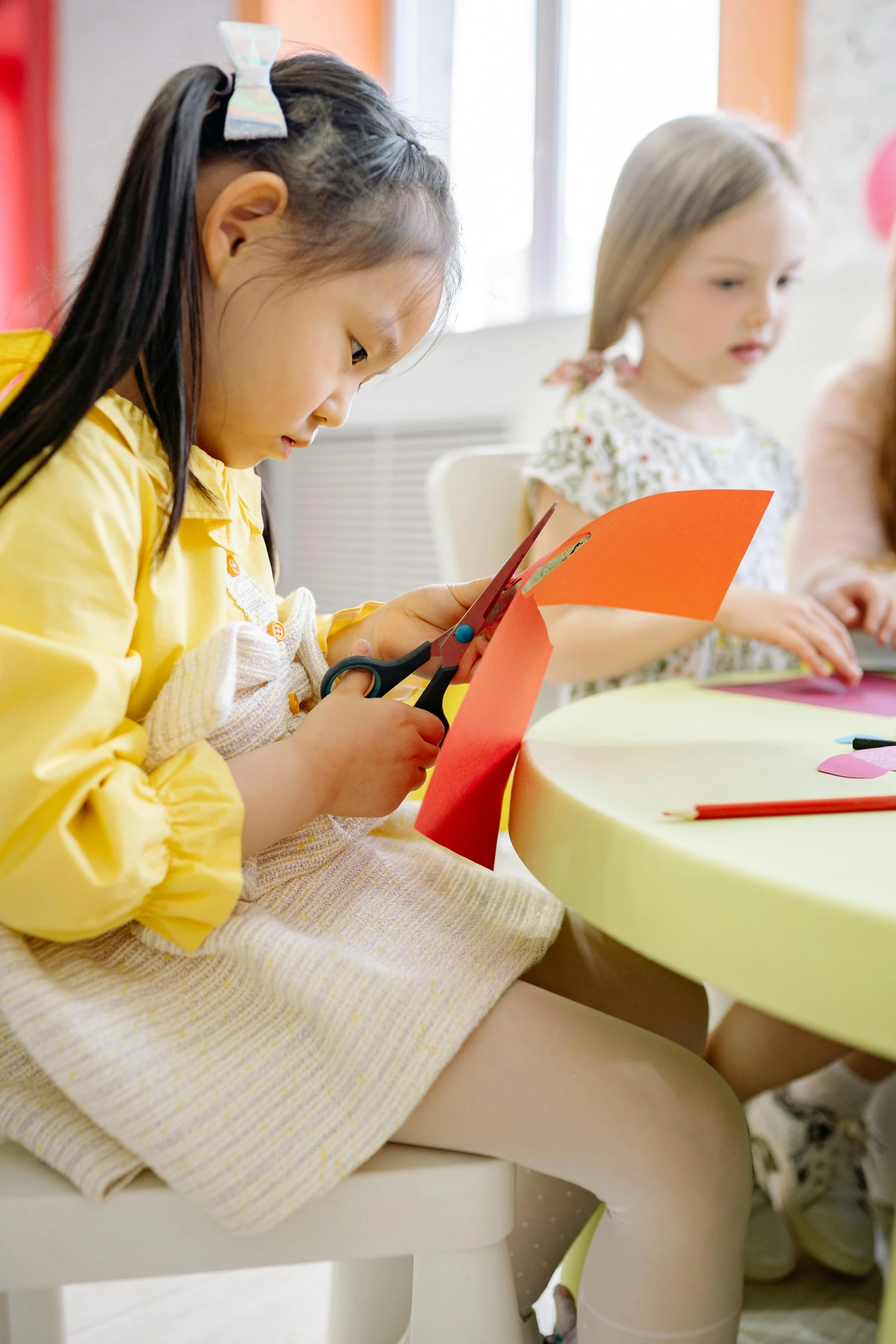 a group of children sitting around a table, on a yellow paper, lady using yellow dress, paper craft, thumbnail