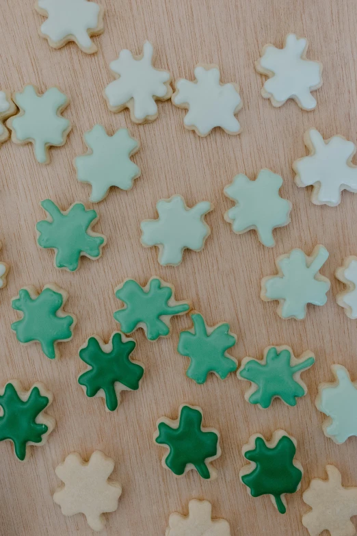 a bunch of cookies sitting on top of a wooden table, gradient green, clover, clear shapes, canadian maple leaves