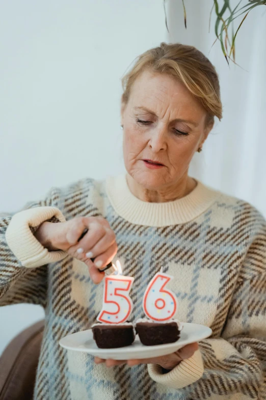 a woman holding a plate with two cupcakes on it, pexels, hyperrealism, he is about 6 0 years old, dripping candles, alexa65, gif