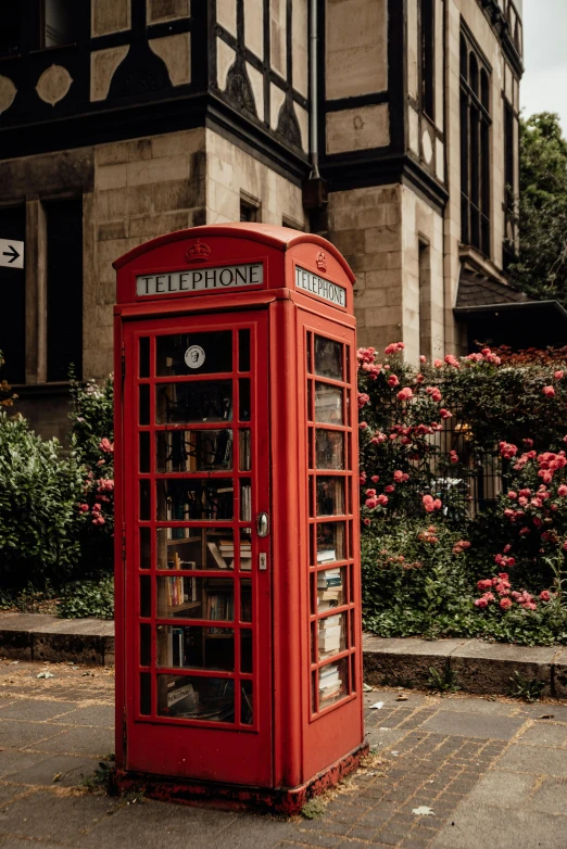a red telephone booth sitting in front of a building, lush surroundings, square, old english, 2019 trending photo