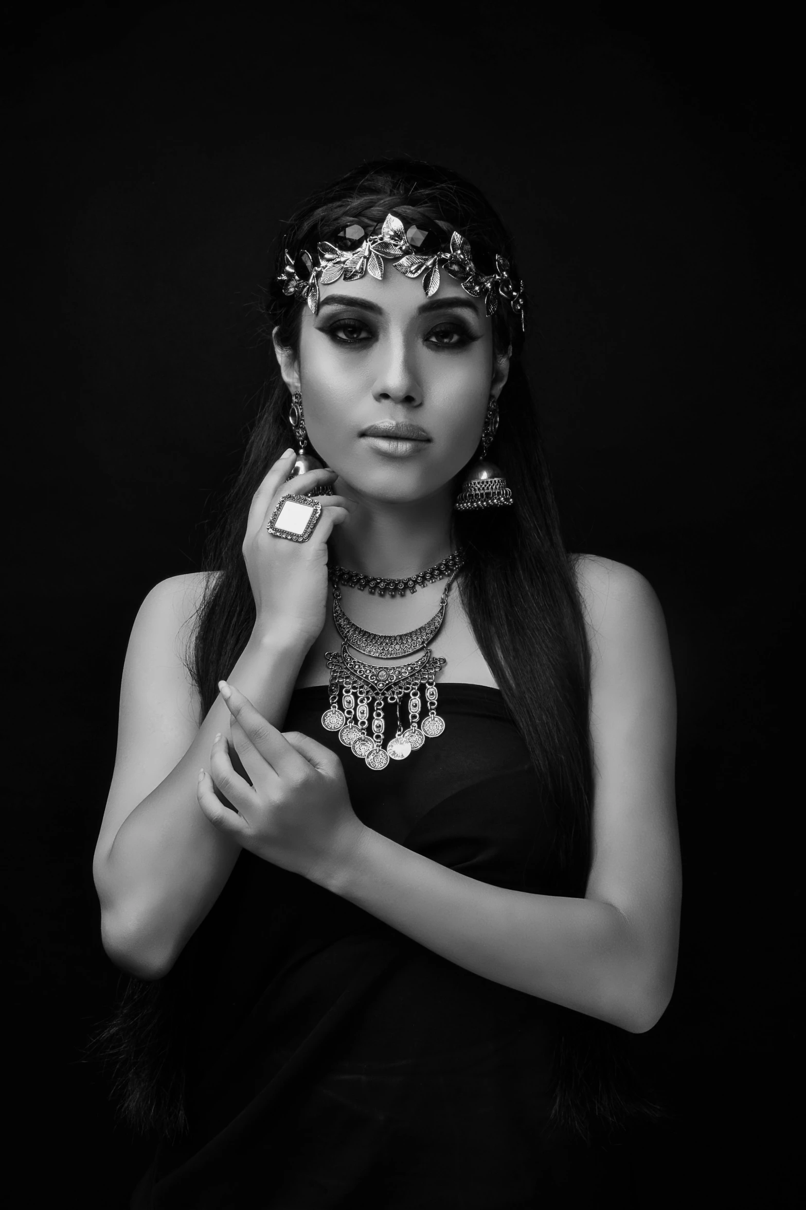 a woman in a black dress posing for the camera, a black and white photo, inspired by irakli nadar, pexels contest winner, tribal jewelry, maya ali as d&d mage, studio!! portrait lighting, ((portrait))