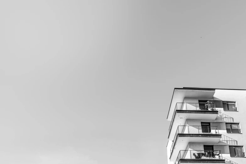 a black and white photo of a tall building, unsplash, minimalism, cloudless sky, balconies, landscape photo, white houses