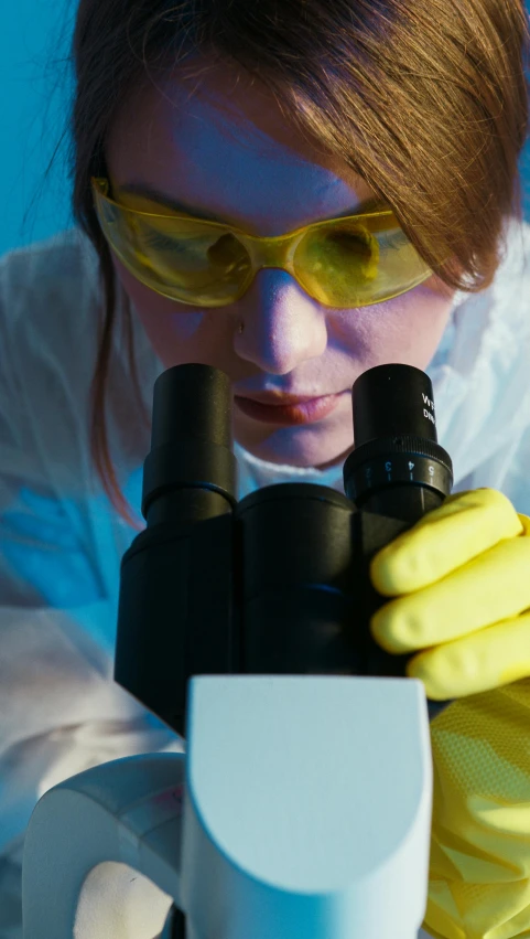 a woman in yellow gloves looking through a microscope, shutterstock, high quality screenshot, tight, getty images, worksafe. cinematic