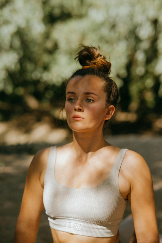 a woman in a sports bra top holding a frisbee, a portrait, pexels contest winner, pensive expression, girl with messy bun hairstyle, in nature, headshot profile picture