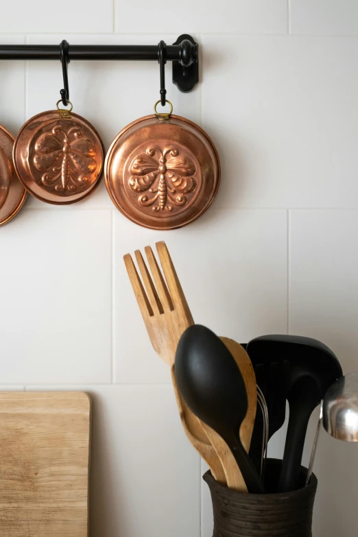 pots and pans hanging on a wall in a kitchen, a still life, inspired by Peter de Sève, unsplash, renaissance, detailed product image, close up bust shot, back - shot, bronze poli