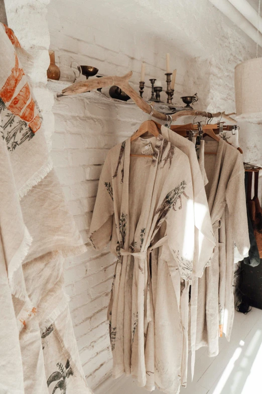 a bunch of robes hanging on a wall, inspired by Marià Fortuny, trending on pexels, in a white boho style studio, shelves full of medieval goods, snapchat photo, clay